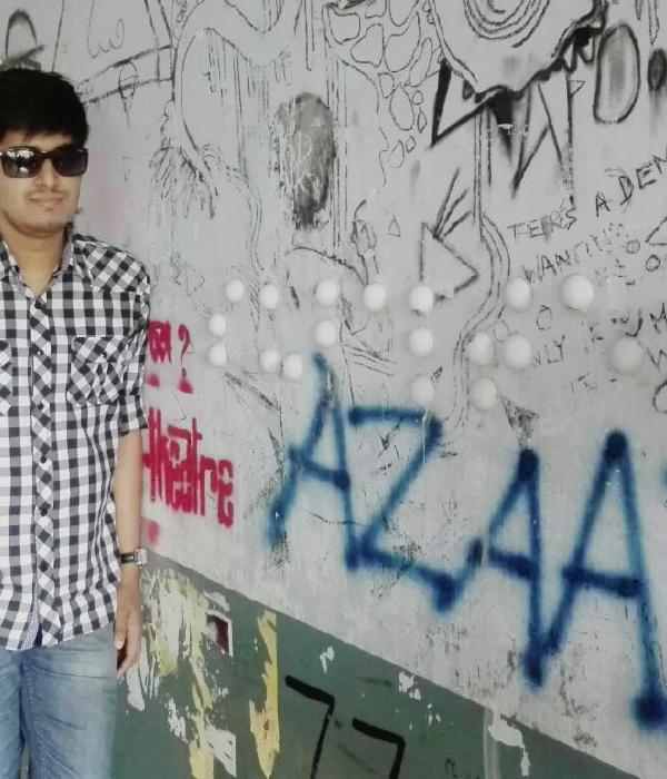 Ishan Chakraborty on the street, standing next to a braille inscription on a wall.